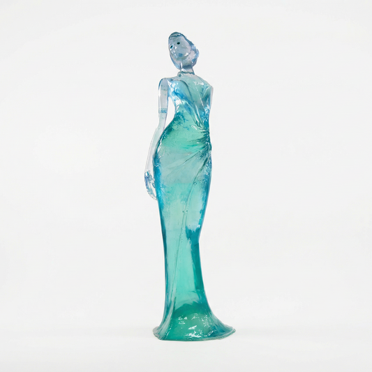 Glass figurine of a woman in a teal dress on a white background